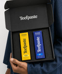 Teefpaste toothpaste packaging in a black box held by a person wearing a denim jacket.